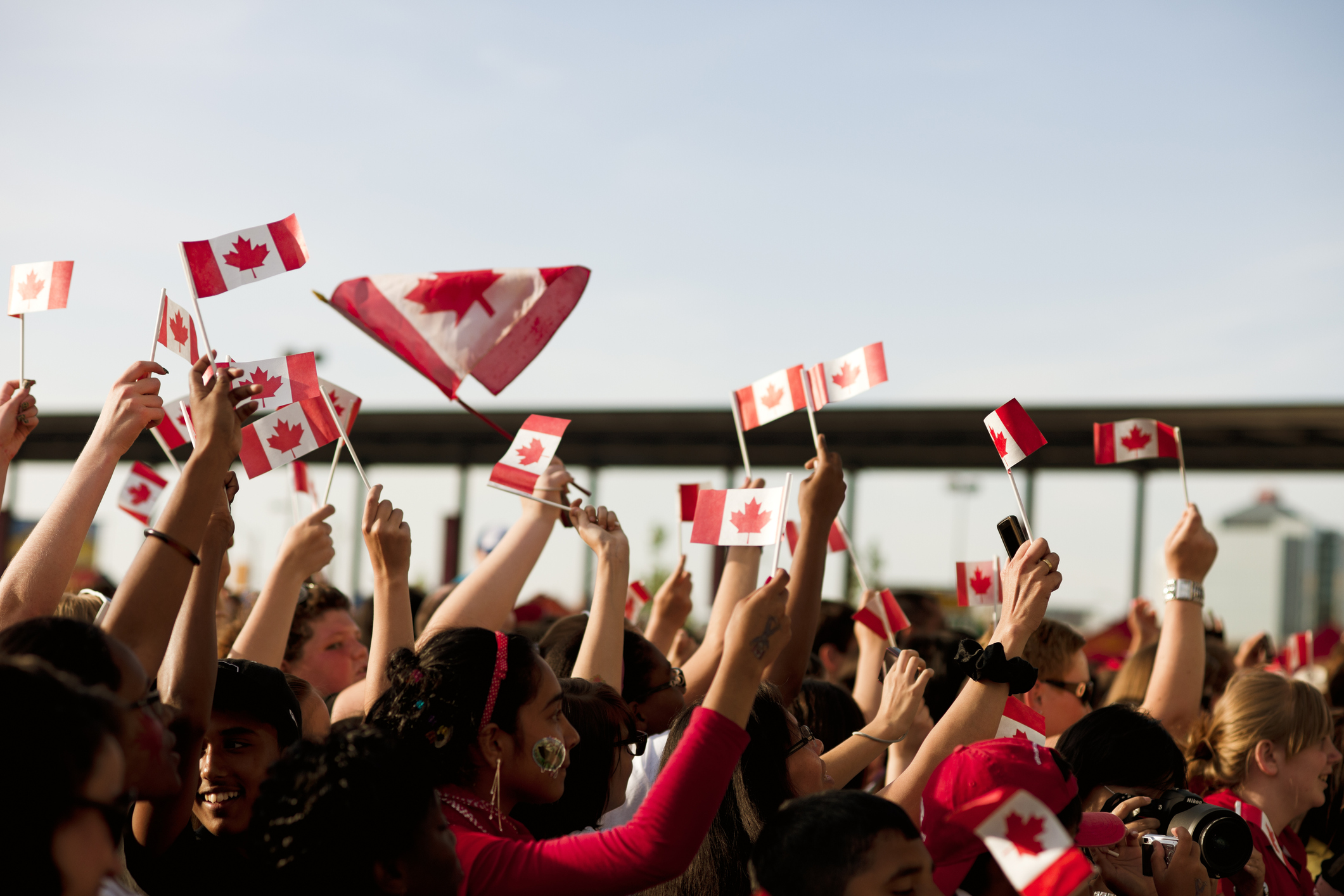 crowd of canadians waving small canada flags during canada day celebrations