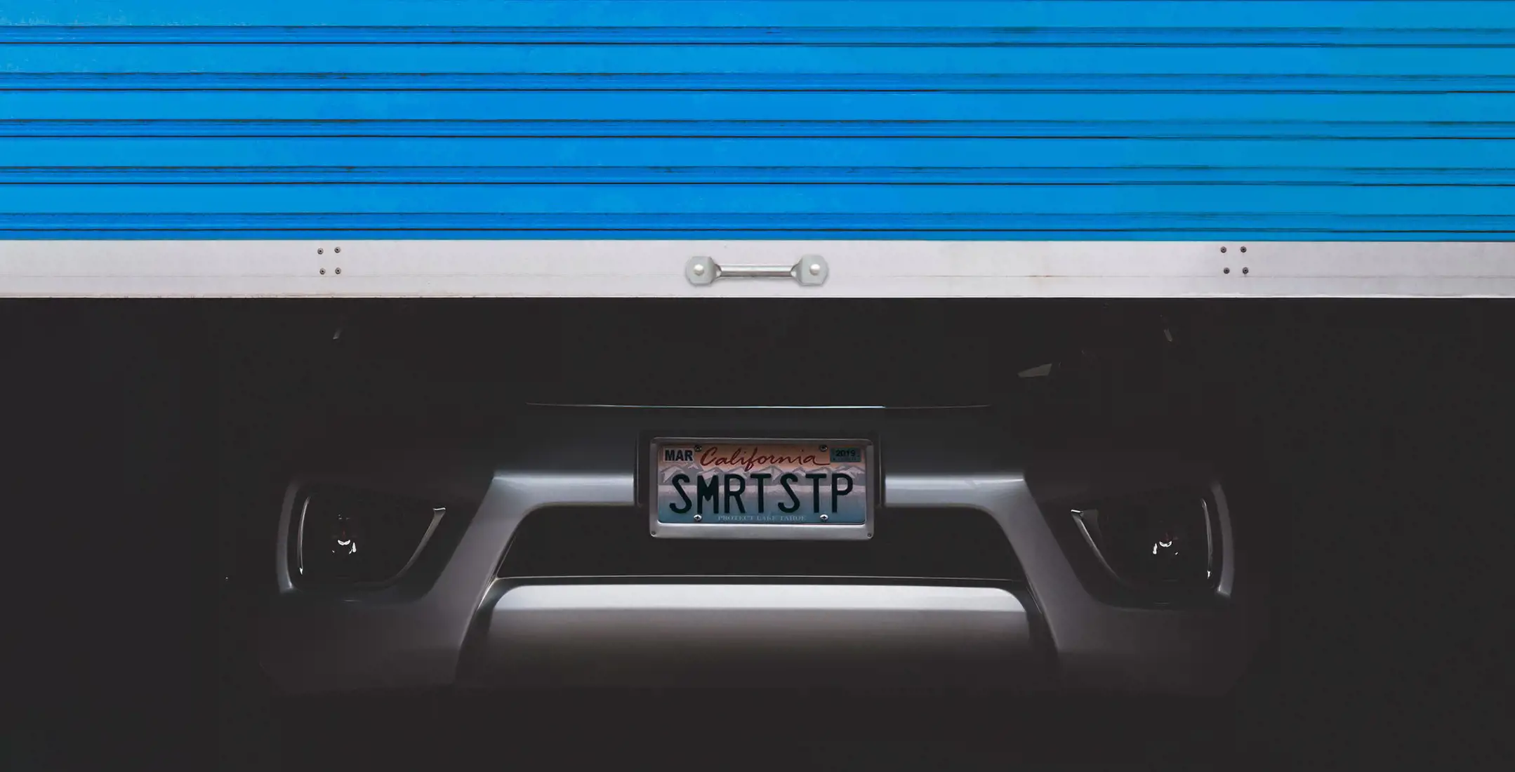 Image of self storage unit with door paritally opened and car parked inside