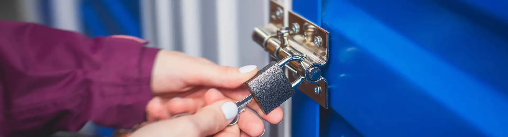 person inserting key into lock on self-storage unit door