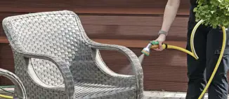 person using hose to clean outdoor furniture