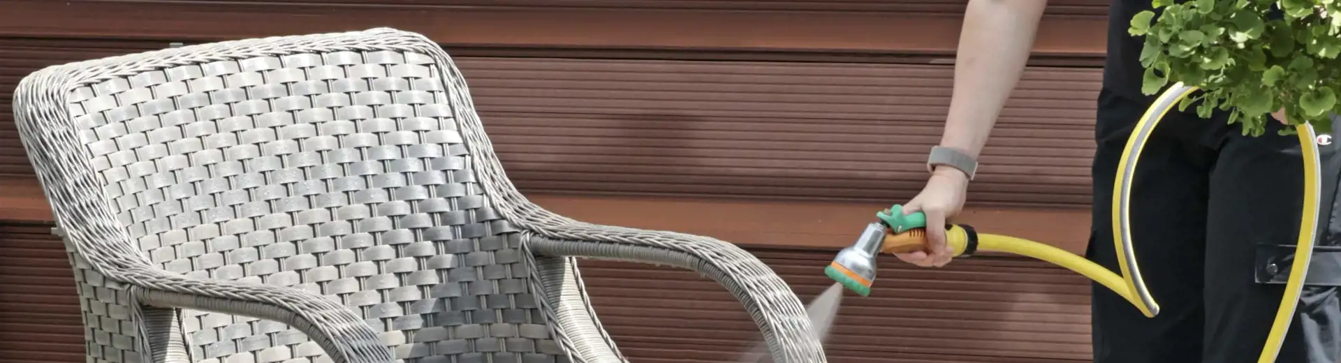person using hose to clean outdoor furniture