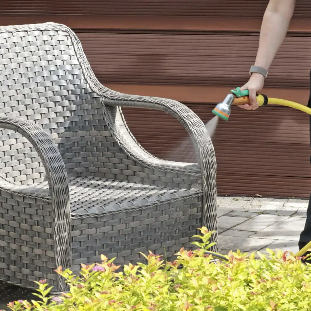 person using hose to clean outdoor furniture
