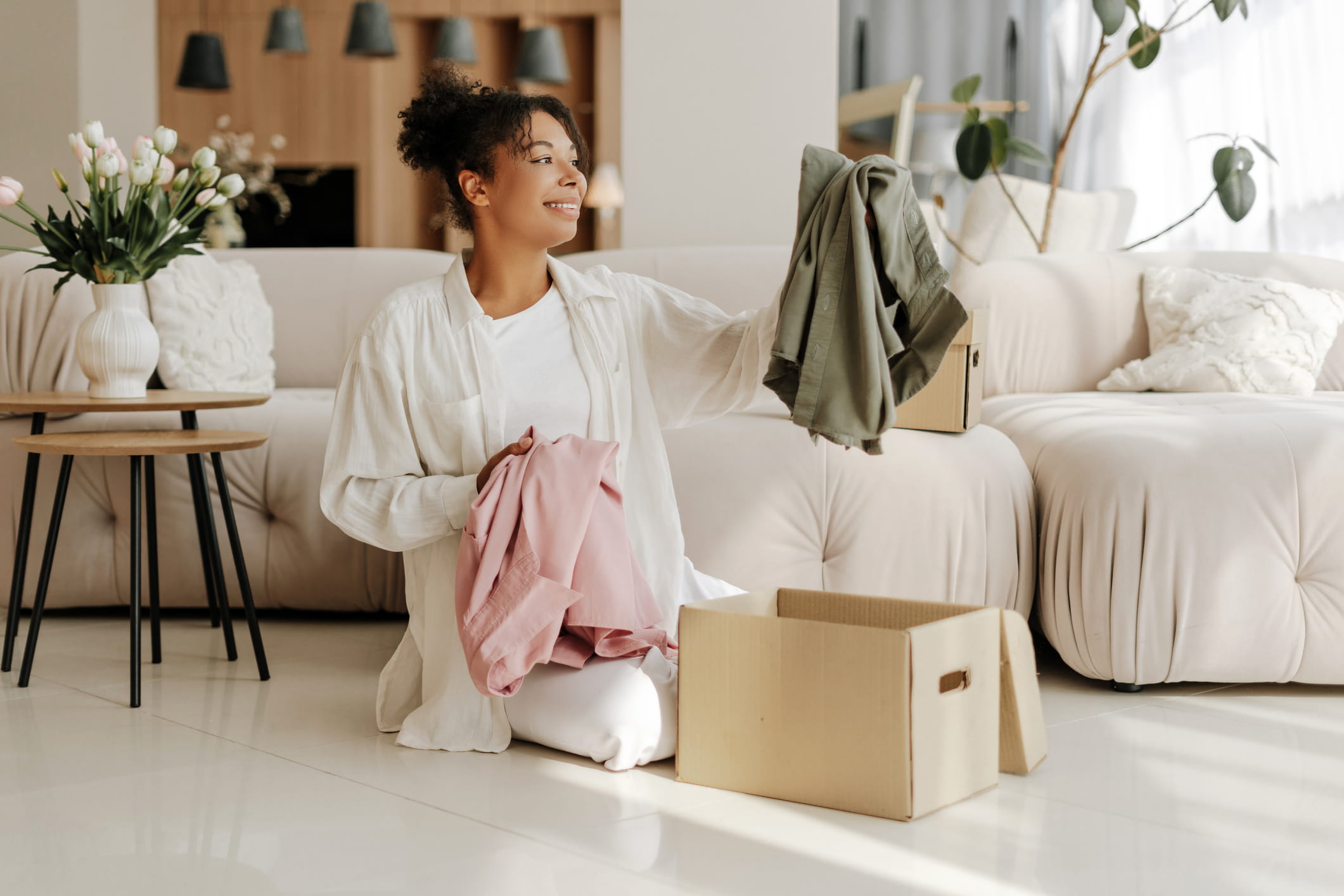woman in clean living room organizing clothes before putting them in box