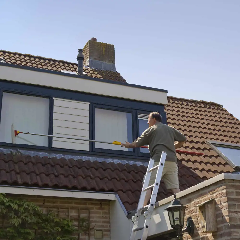 man standing on ladder cleaning home windows