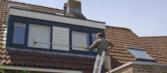 man standing on ladder cleaning home windows