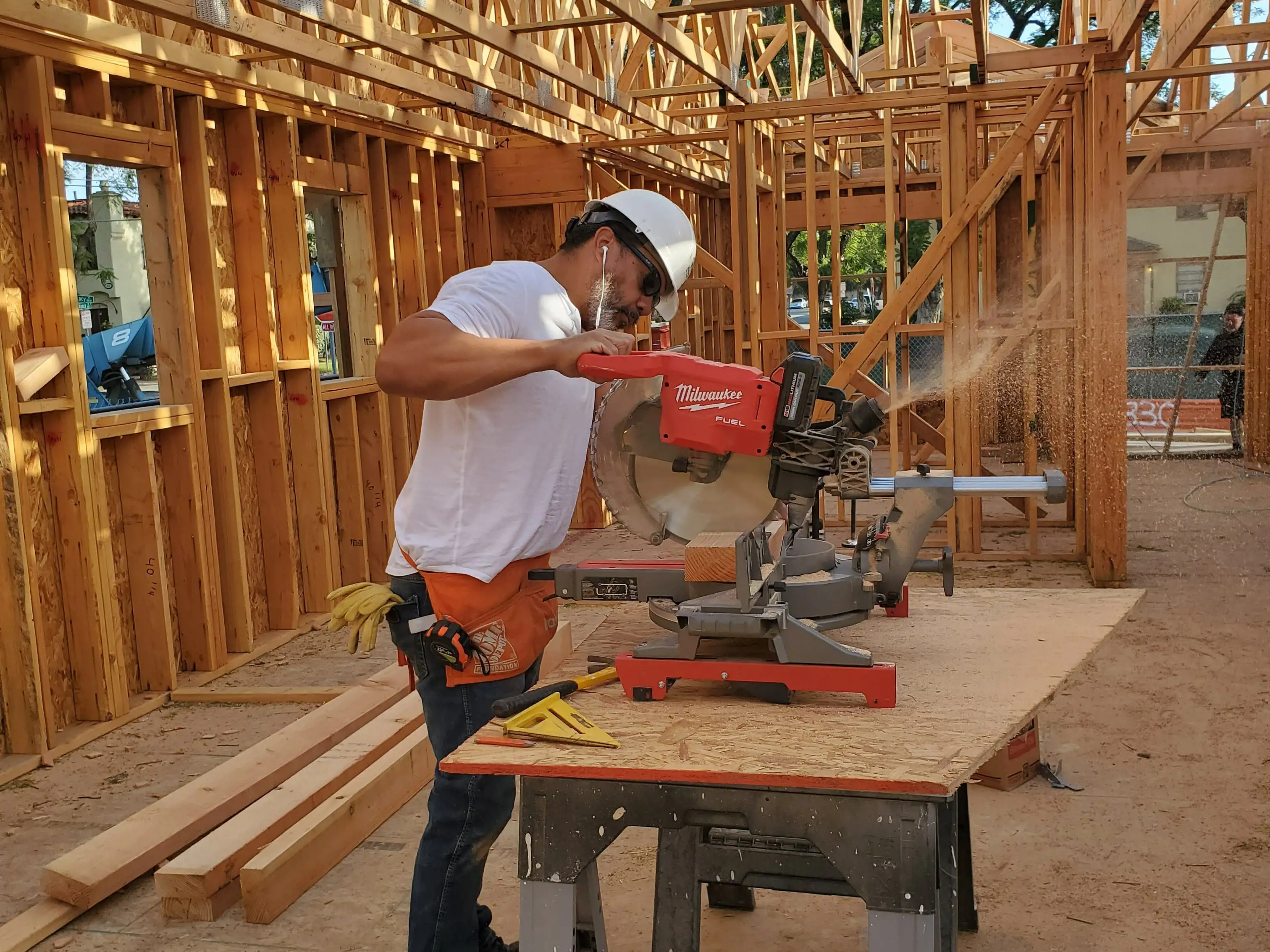 Un employé de SmartStop utilise une scie à onglet pour aider à construire une maison pour Habitat pour l'humanité
