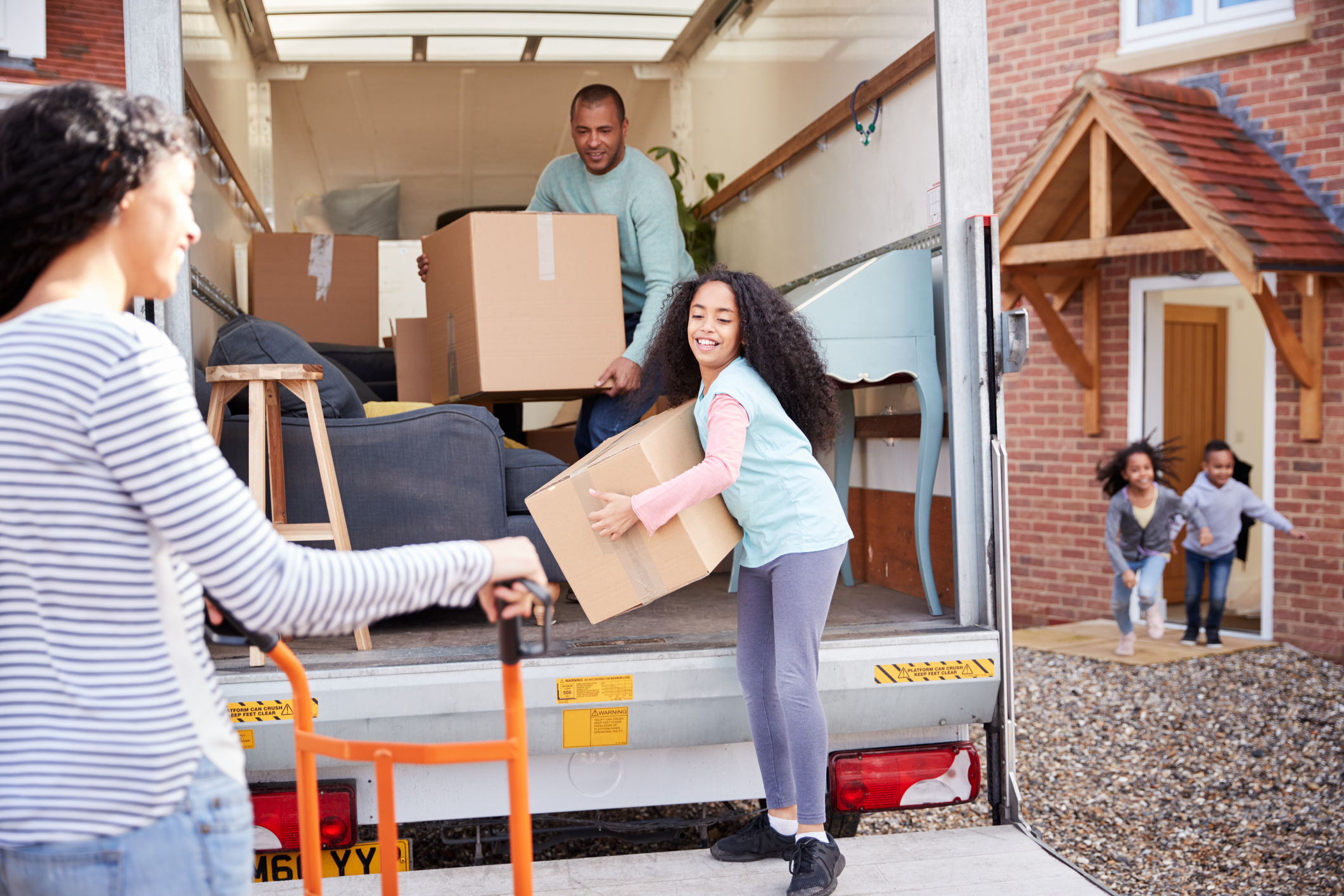 family with children packing up a large moving truck with boxes and household belongings