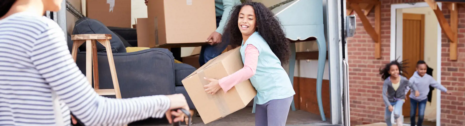 family with children packing up a large moving truck with boxes and household belongings