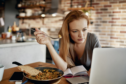 woman eating while reading on her computer