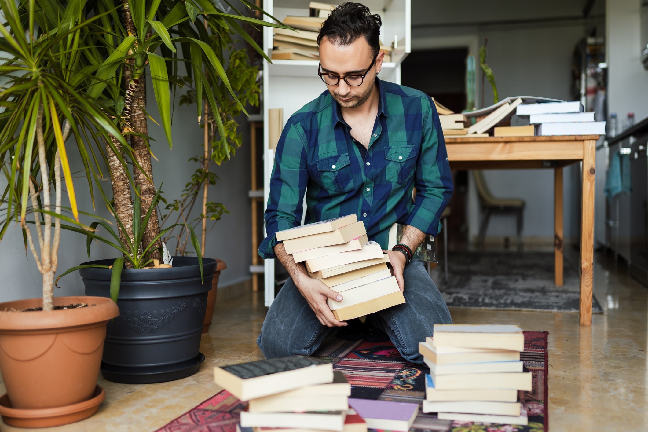 homme portant des lunettes organisant une pile de livres