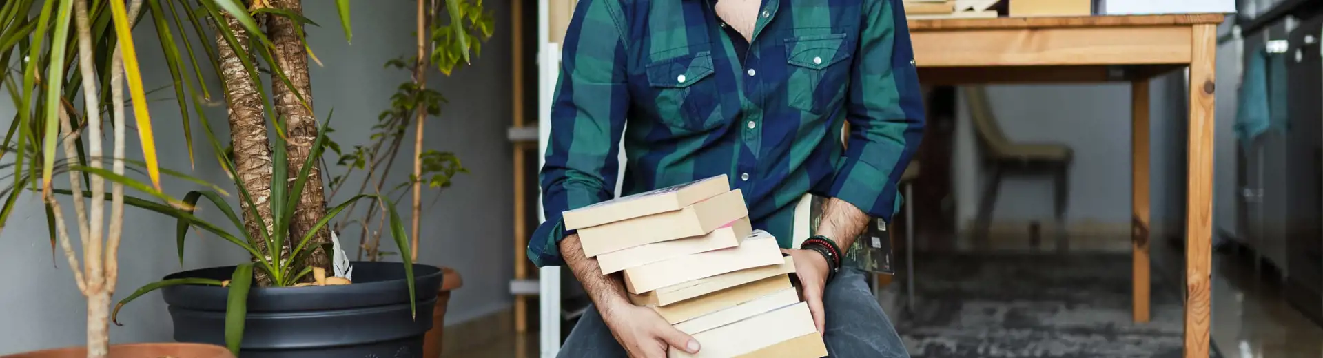 man wearing glasses organizing pile of books