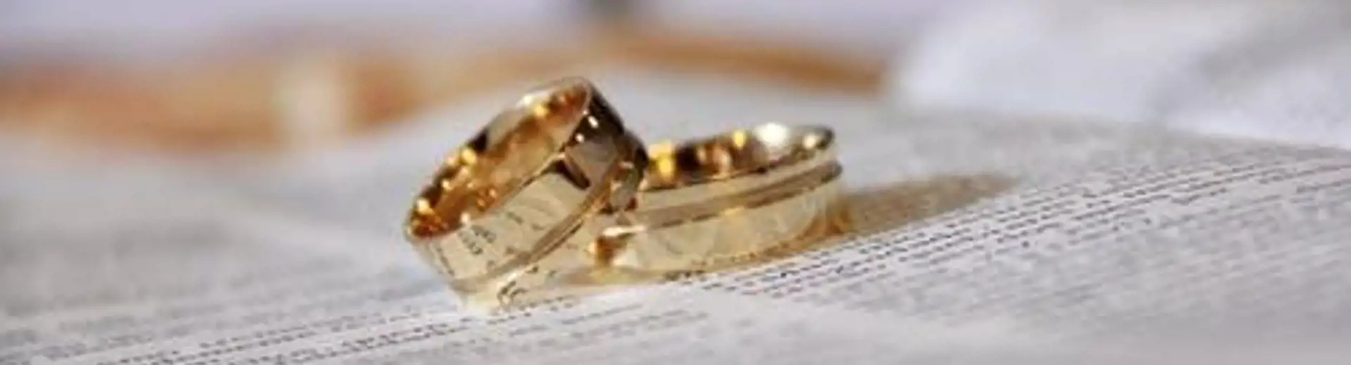 Une image de deux alliances en or, posées sur une pile de papiers.