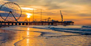 Image of ocean pier with ferris wheel at sunset