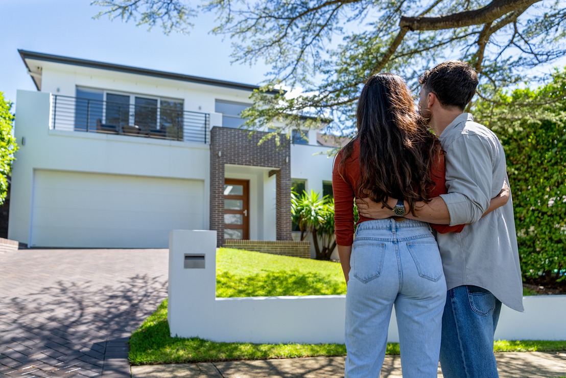young couple looking at their new home from the curb