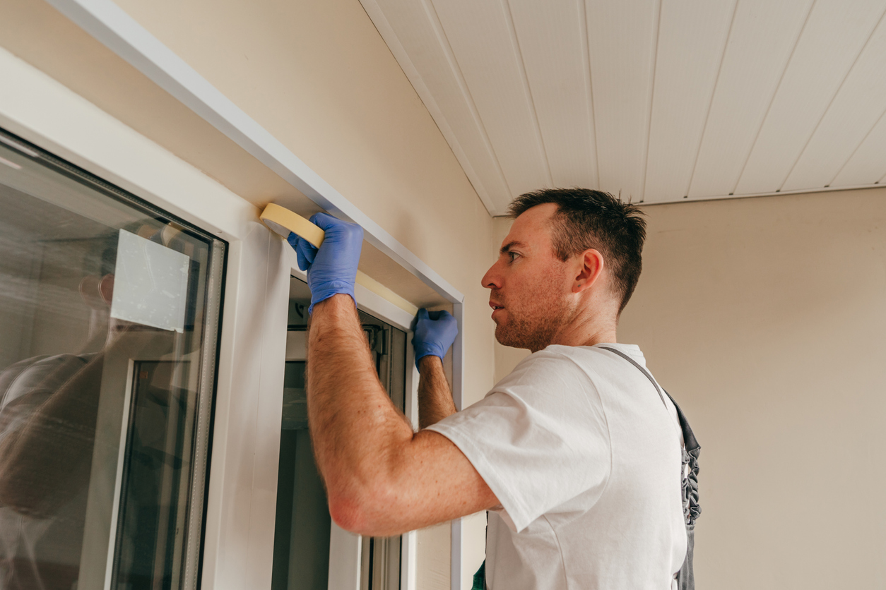 homme ajoutant du ruban de montage sur le bord de la fenêtre avant de la sceller