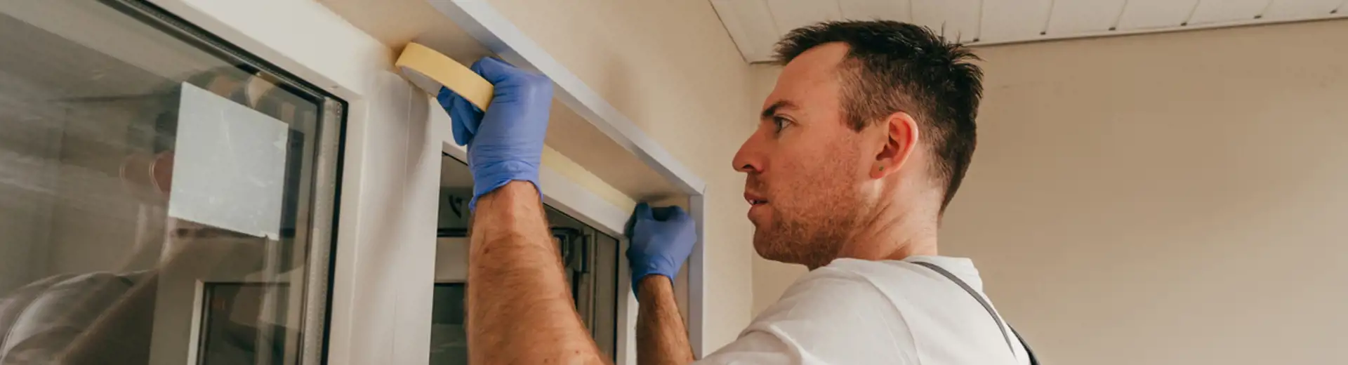 homme ajoutant du ruban de montage sur le bord de la fenêtre avant de la sceller