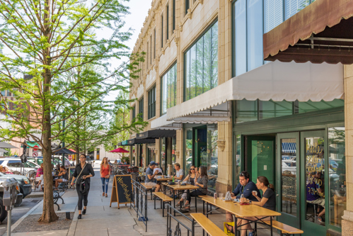 people dining outside along busy sidewalk