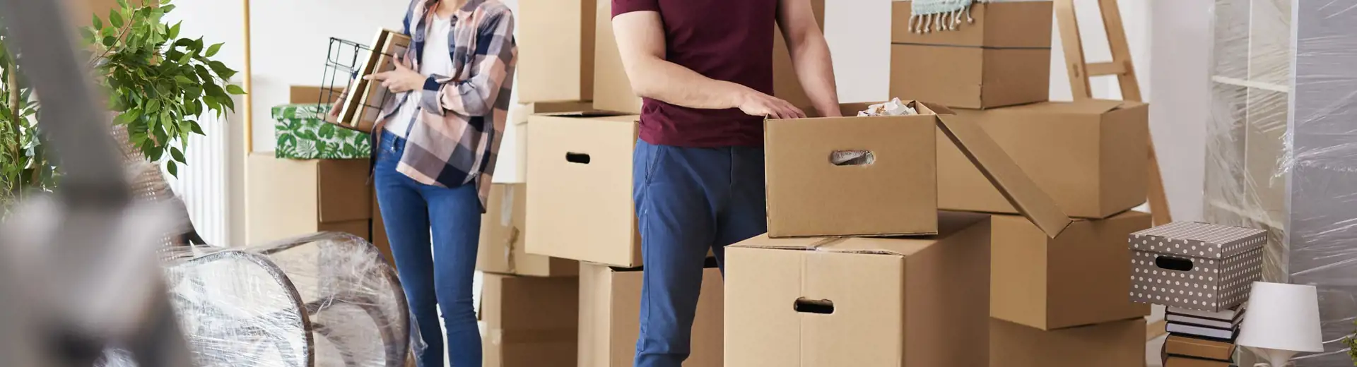 couple avec petit chien transportant des cartons lors du déménagement dans une nouvelle maison