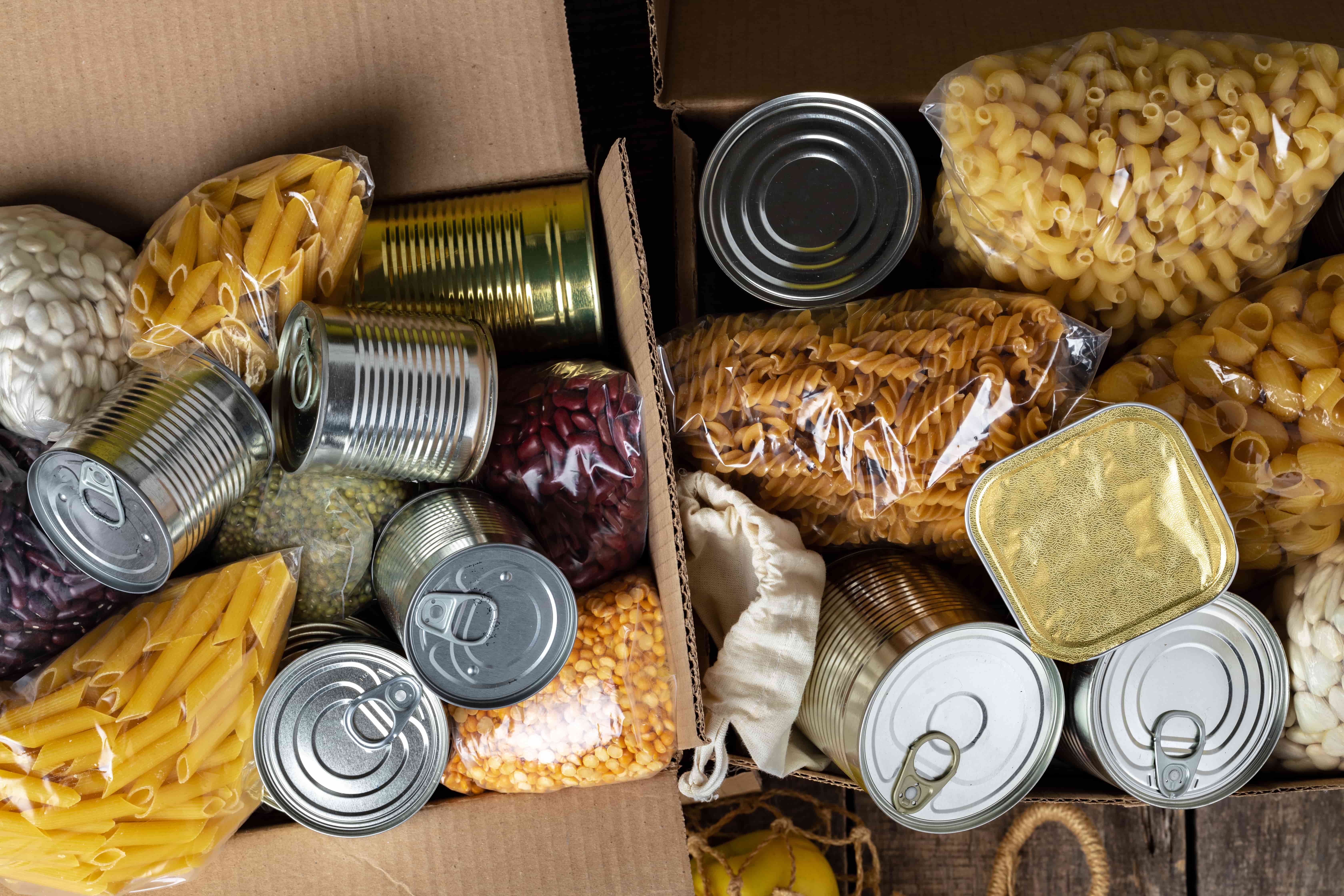 assortment of dried pasta and canned foods in cardboard boxes