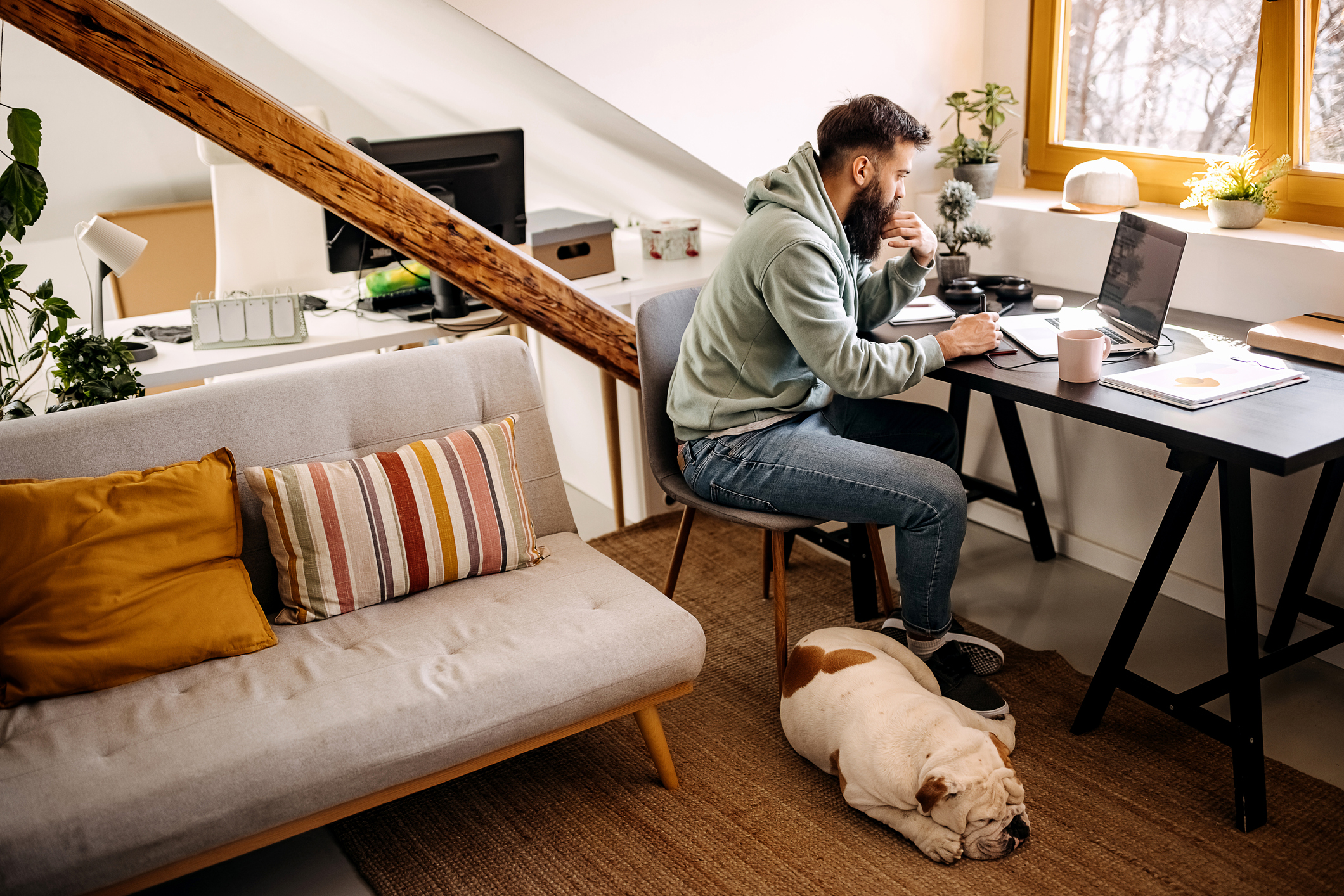 homme dans un petit appartement travaillant à son bureau avec un chien se reposant à ses pieds