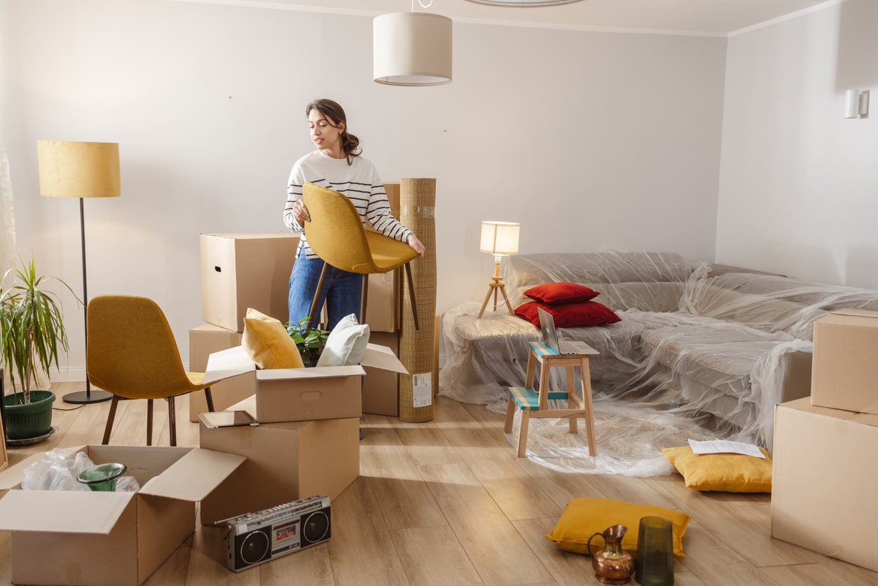 woman holding chair as she moves into apartment