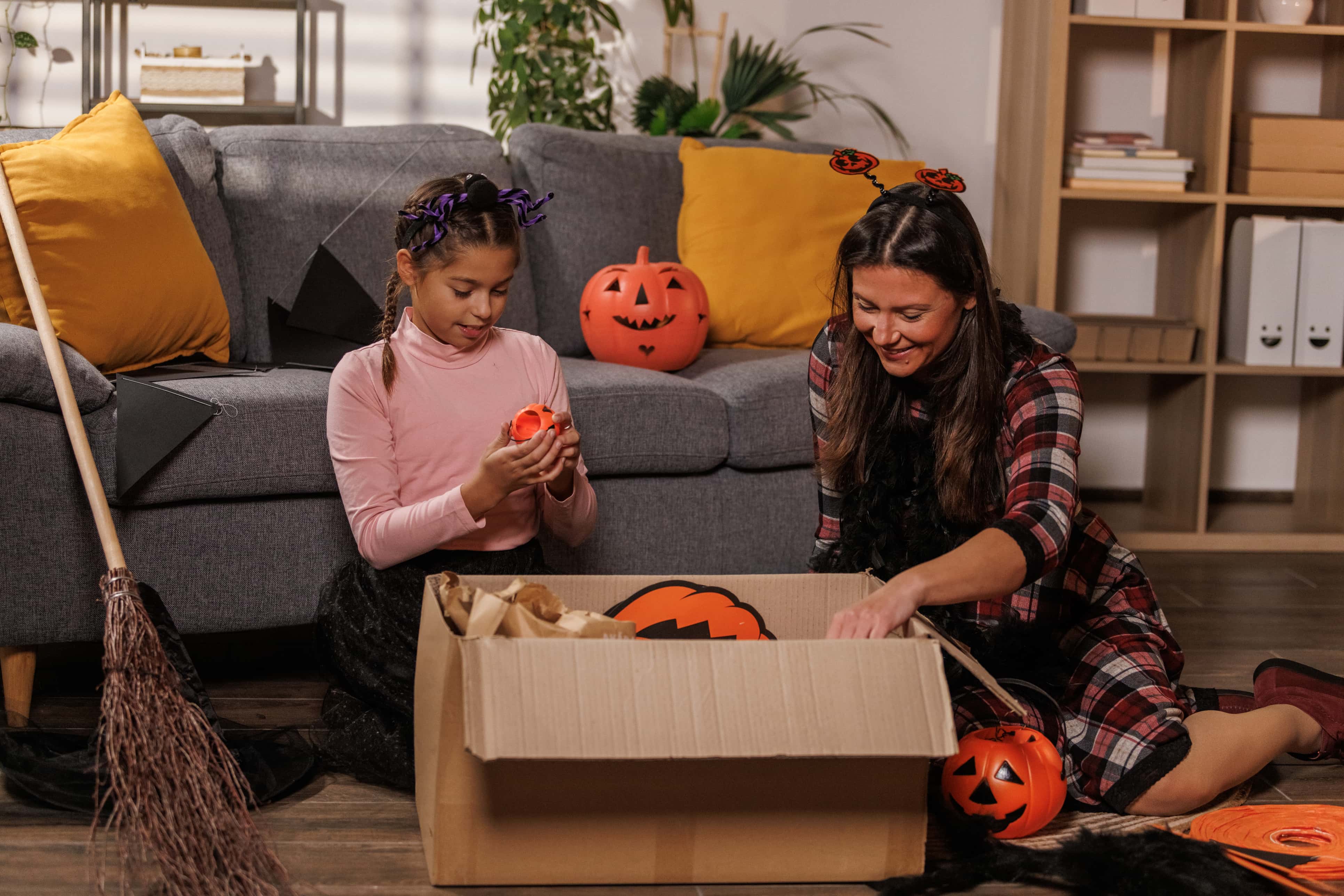 mom and daughter packing halloween decorations into cardboard box