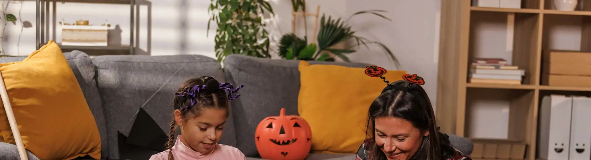 mom and daughter packing halloween decorations into cardboard box