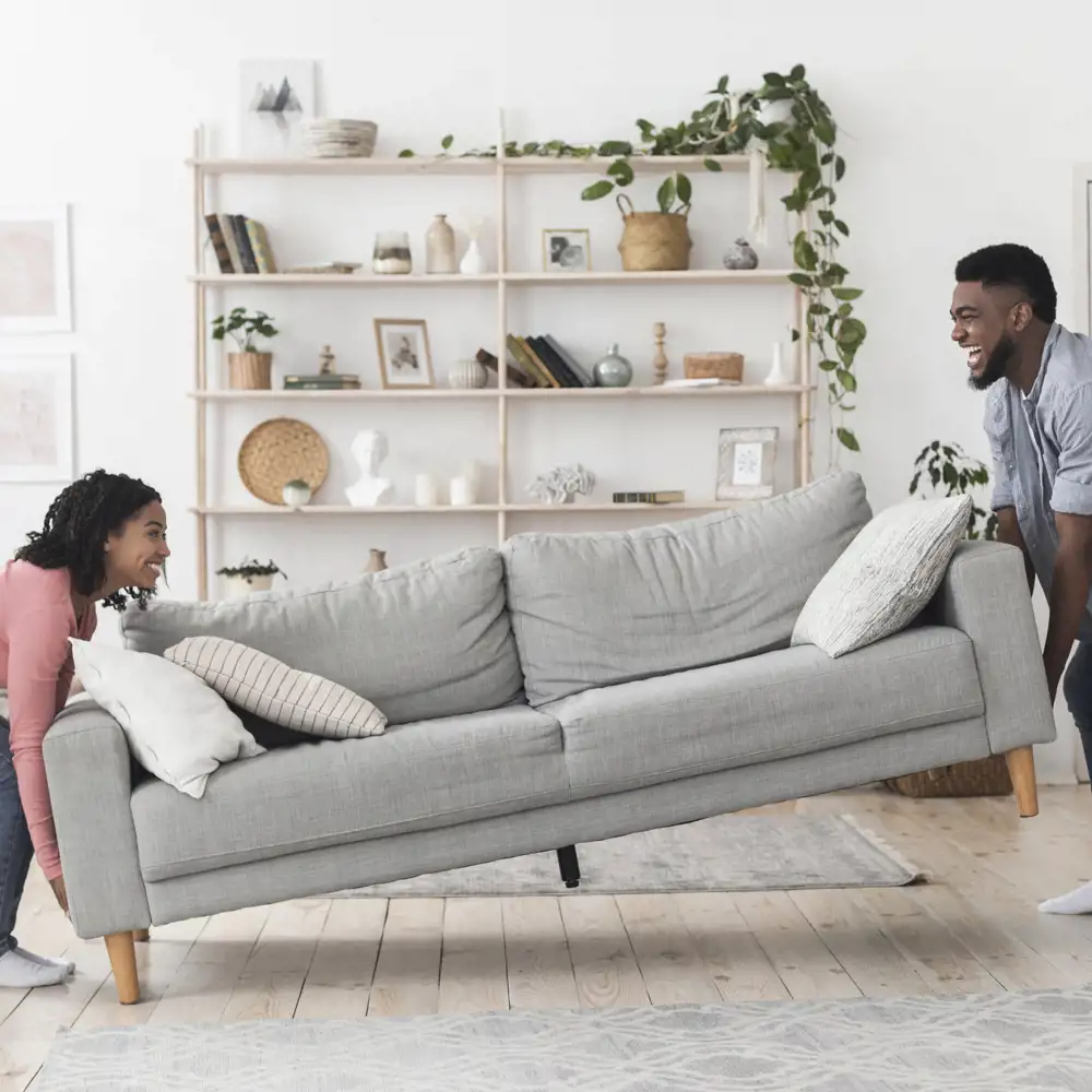 couple carrying couch in living room