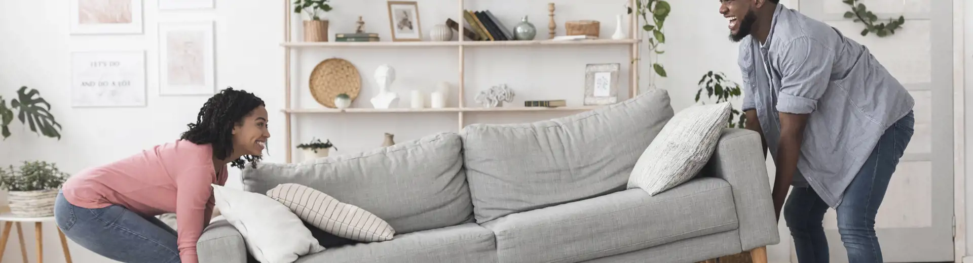 couple carrying couch in living room