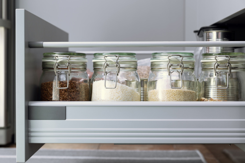 glass jars of dry ingredients stored in a pull-out kitchen drawer