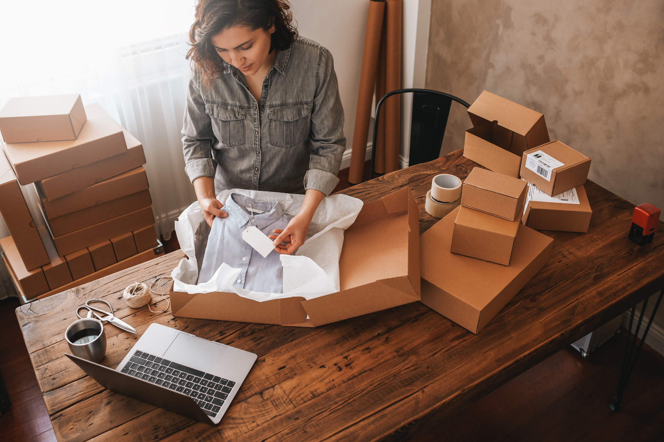 woman packing vintage shirt into a box at home studio