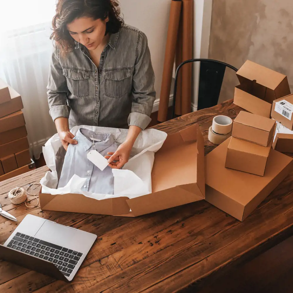 woman packing vintage shirt into a box at home studio