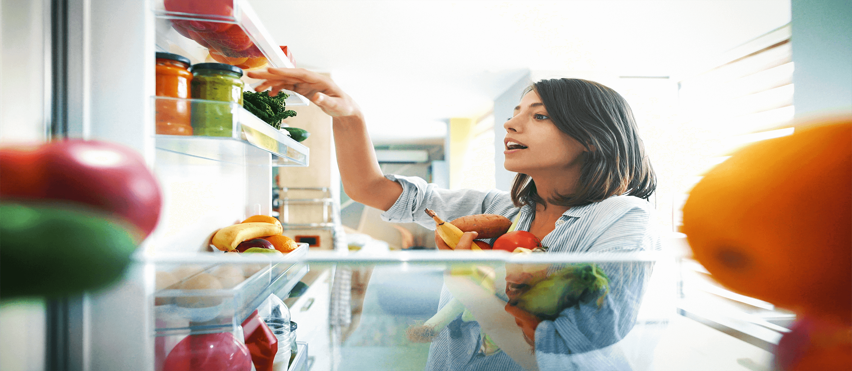 Image of girl grabbing healthy vegetables inside a refrigerator