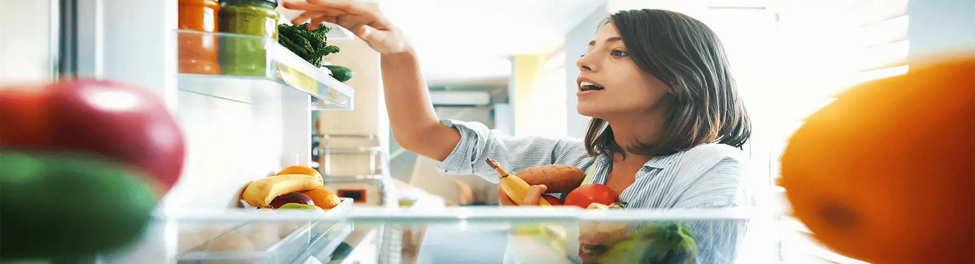 Image of girl grabbing healthy vegetables inside a refrigerator