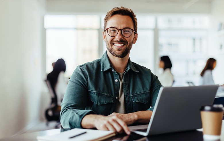 image of smiling man working on his laptop 