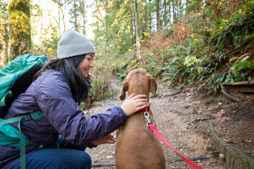 woman petting dog while on hike