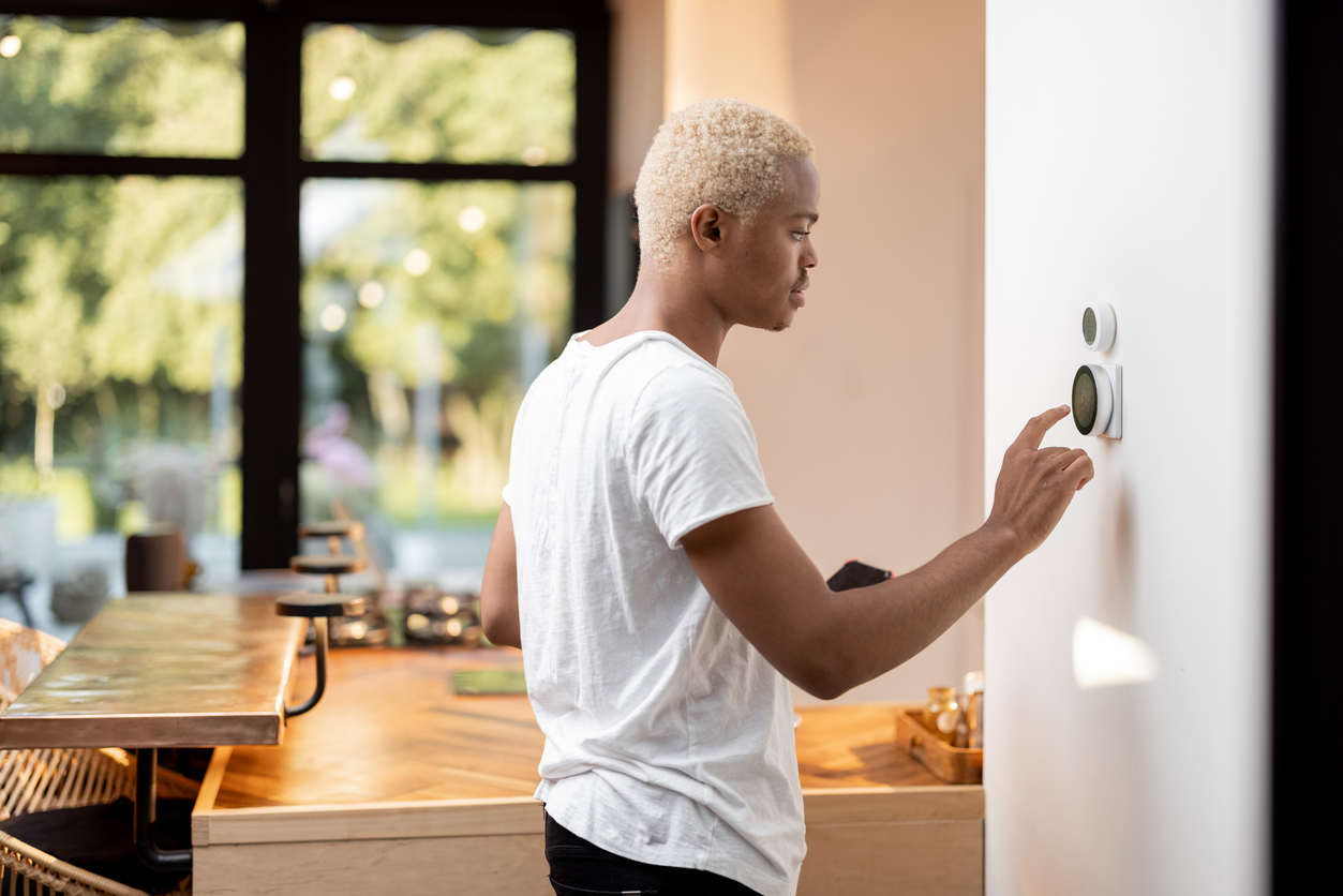 young man uses smart home assistant device on wall next to kitchen