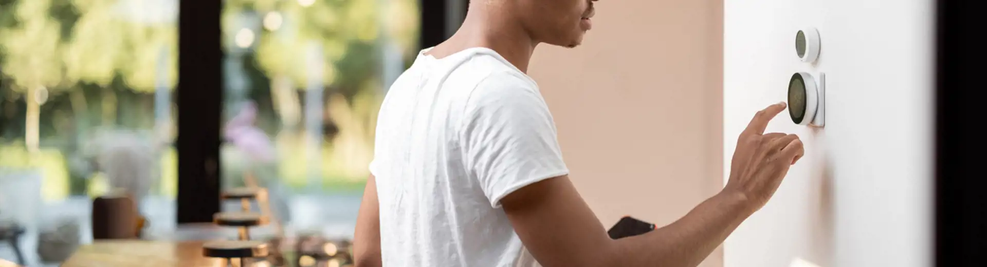 young man uses smart home assistant device on wall next to kitchen