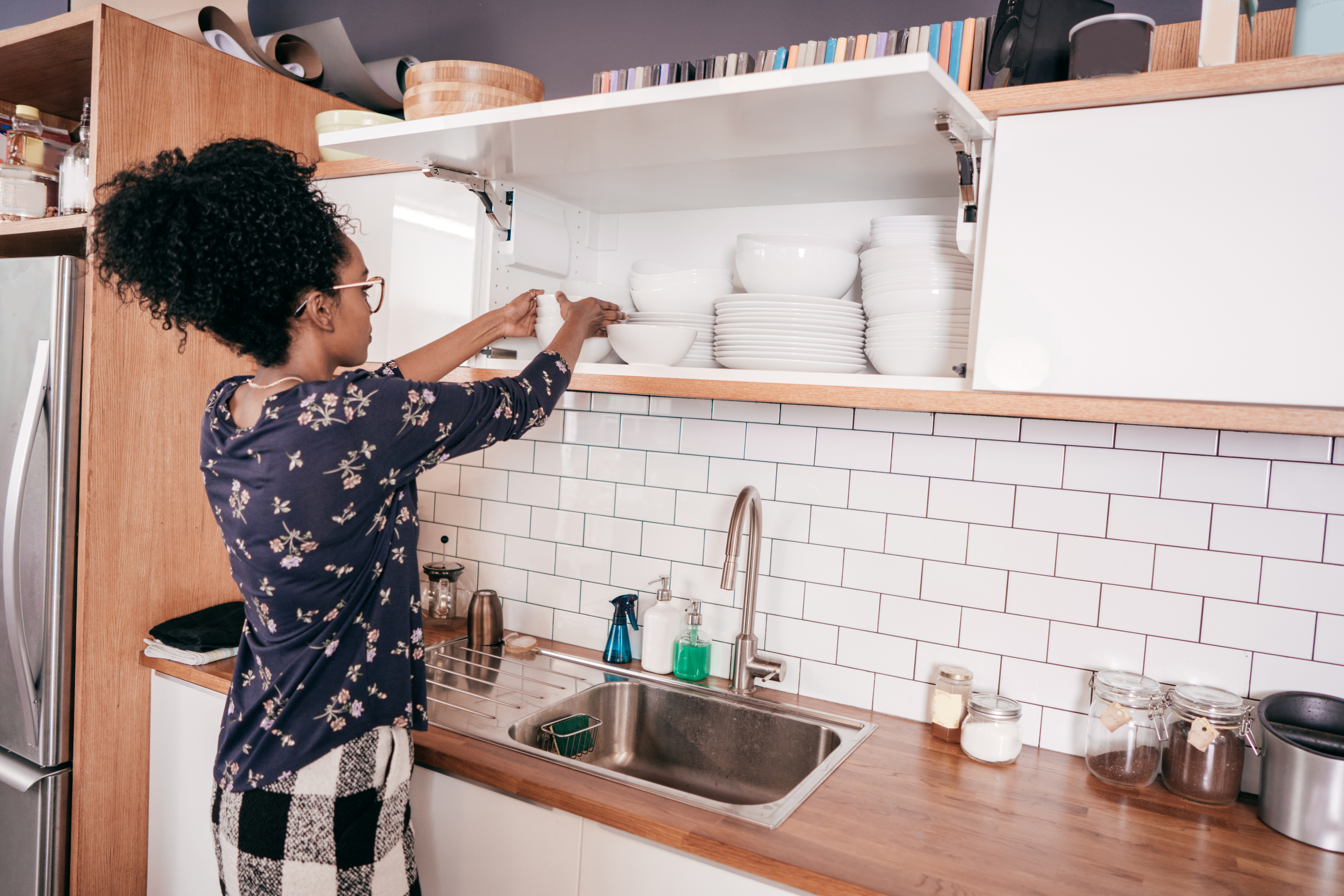 woman organizing dishes on a shelf in kitchen
