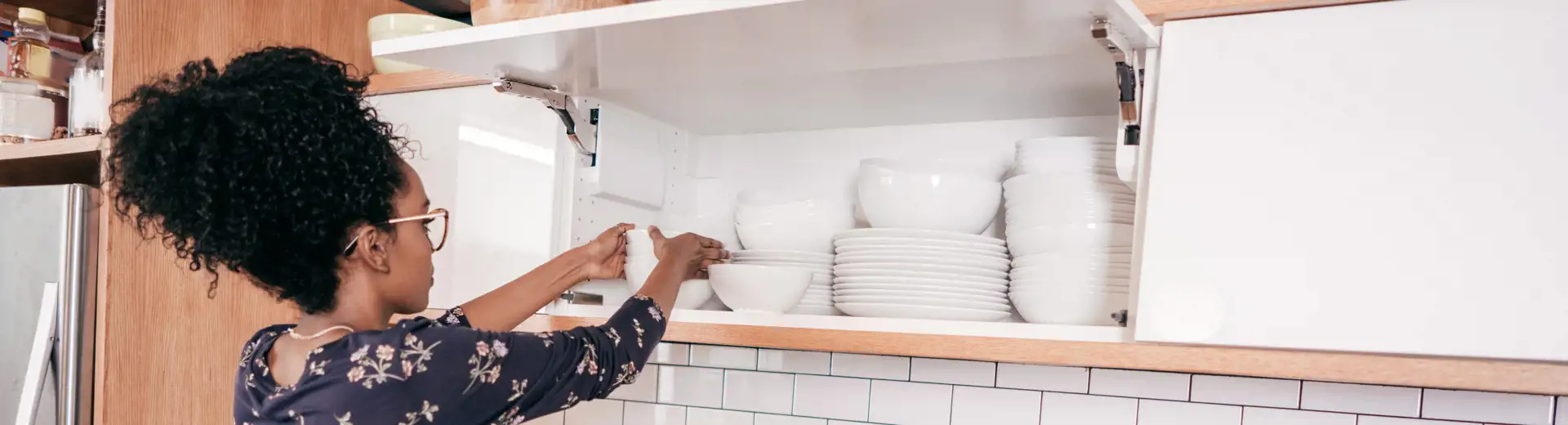 woman organizing dishes on a shelf in kitchen