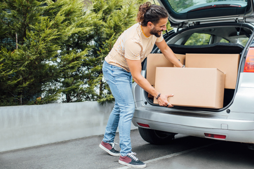 man loading trunk of car with boxes