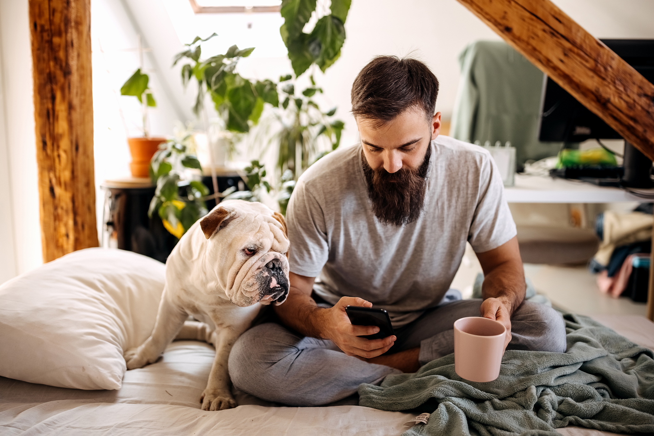 chien et propriétaire sur le lit pendant que le propriétaire boit du café